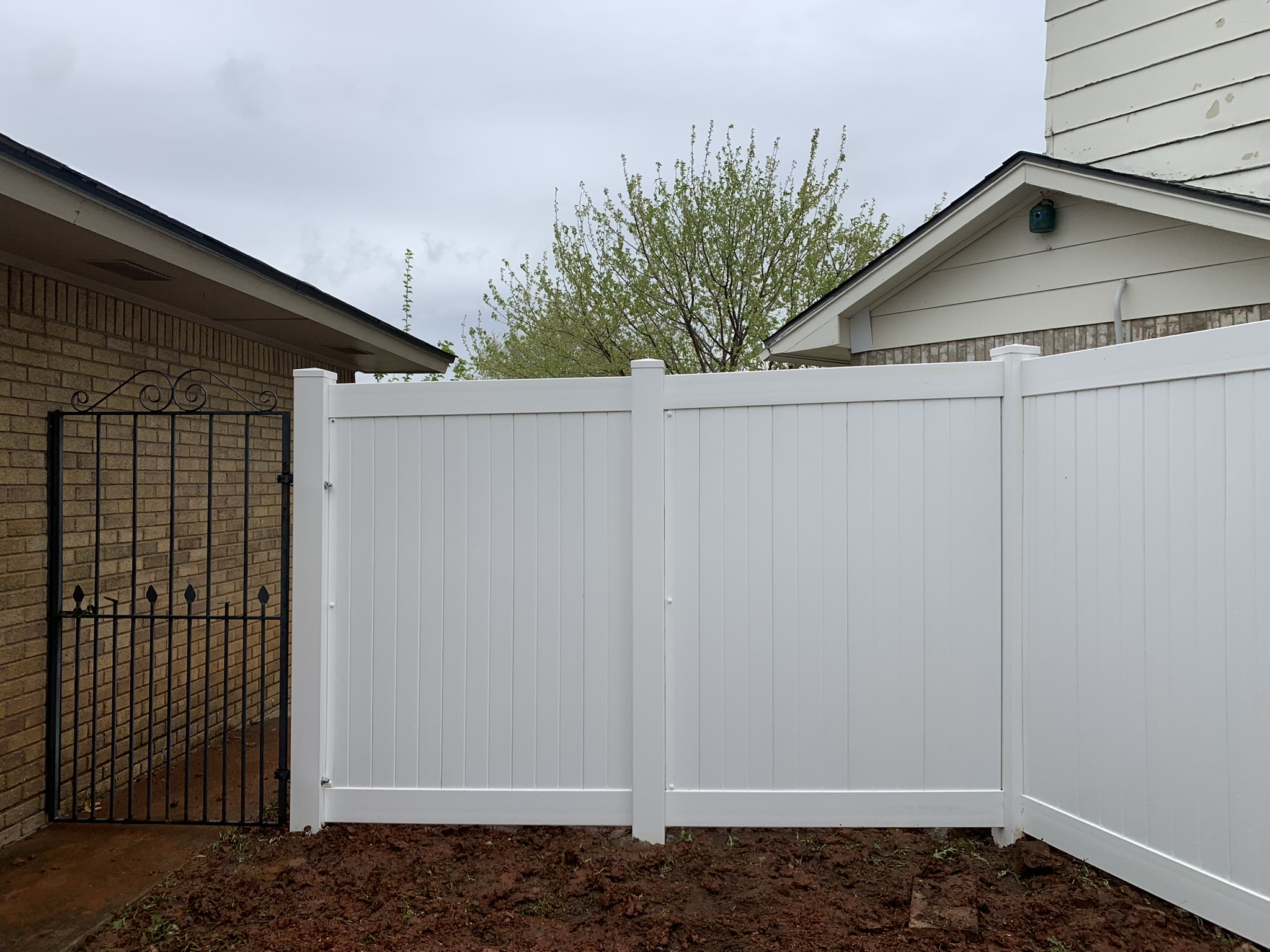 White vinyl fence installation by Midland Vinyl Products near me in Oklahoma County, featuring a black gate
